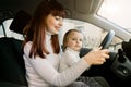 Mother with little baby girl sitting in front seat and driving car together. Child in danger, no safety on the road