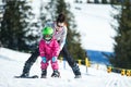 Mother and little child skiing in Alps mountains. Active mom and toddler kid with safety helmet, goggles and poles. Royalty Free Stock Photo