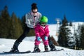 Mother and little child skiing in Alps mountains. Active mom and toddler kid with safety helmet, goggles and poles.