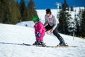 Mother and little child skiing in Alps mountains. Active mom and toddler kid with safety helmet, goggles and poles.