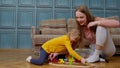 Mother with little daughter child girl riding toy train on wooden railway blocks board game at home