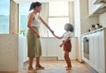 Mother and little daughter dancing having active fun together in the kitchen at home. Child and nanny having fun dancing Royalty Free Stock Photo