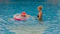 The mother with little daughter have fun in the pool. Mom plays with the child. The family enjoy summer vacation in a Royalty Free Stock Photo