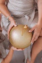 Mother and little daughter holding huge golden holiday ball