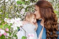 Mother and little daughter hugging each other and walking in blooming apple garden. Mom loves her child. Spring story. Happy Royalty Free Stock Photo