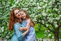 Mother and little daughter hugging each other and walking in blooming apple garden. Mom loves her child. Spring story. Happy Royalty Free Stock Photo