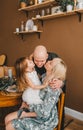 Mother and little daughter kissing father on cheek, sitting in living room on cozy chair