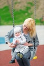 Mother and the little daughter shake on a swing.