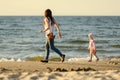 Mother and little daughter walking on the beach