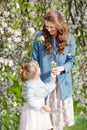 Mother and little daughter walking in blooming apple garden. Mom loves her child. Spring story. Happy family in beautiful spring Royalty Free Stock Photo