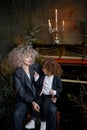 Mother with little daughter wearing stylish clothes on the background piano and candlestick