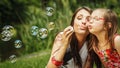 Mother and little girl blowing soap bubbles in park. Royalty Free Stock Photo