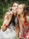 Mother and little girl blowing soap bubbles in park. Royalty Free Stock Photo