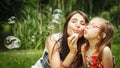 Mother and little girl blowing soap bubbles in park. Royalty Free Stock Photo