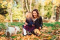 Mother and little girl having fun together. Autumn time, weekend and holidays. Family playing with dog in autumn leaves Royalty Free Stock Photo