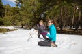 Mother and little girl playing with snowman in nature