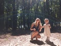 Mother and little girl into the sun light inside the forest