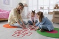 Mother and little girls taping sticker hopscotch on floor Royalty Free Stock Photo