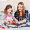 Mother and little kid girl baking gingerbread cookies for Christ Royalty Free Stock Photo