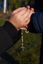 Mother and little son hold each other`s hand with a rosary