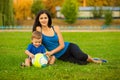 Mother and little son playing ball on grass in park