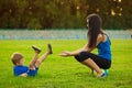 Mother and little son playing ball on grass in park