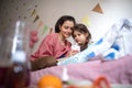 Mother looking after sick small daughter in bed at home.