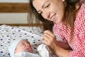 Mother looks at her child. Young mother looking on her newborn baby. Beautiful mom lying at bed with a cute sleeping new born Royalty Free Stock Photo