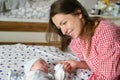 Mother looks at her child. Young mother looking on her newborn baby. Beautiful mom lying at bed with a cute sleeping new born Royalty Free Stock Photo