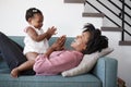 Mother Lying On Sofa At Home Playing Clapping Game With Baby Daughter