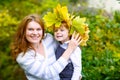 Mother with maple leaf wreath holding little toddler boy in autu Royalty Free Stock Photo