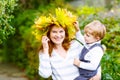 Mother with maple leaf wreath holding little toddler boy in autu Royalty Free Stock Photo