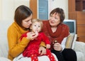 Mother with mature grandmother caring for sick toddler