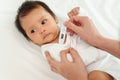 mother measuring temperature at armpit of ill baby. sick child with high fever on bed Royalty Free Stock Photo