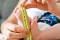 Mother measuring tiny baby foot with a meter