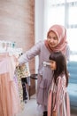 mother muslim choosing a dress for her daughter at clothing store