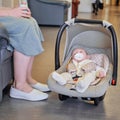 A mother with a newborn baby in a carrier is waiting for a doctor appointment in the lobby of the clinic. The parent keeps the Royalty Free Stock Photo
