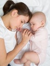 Mother with newborn baby sleeping on the bed at home. Top view, close up. Royalty Free Stock Photo