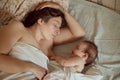 Mother and newborn baby sleeping in bed. Mother kissing baby`s head. Motherhood concept. Royalty Free Stock Photo