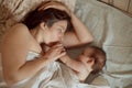 Mother and newborn baby sleeping in bed. Mother kissing baby`s head. Motherhood concept. Royalty Free Stock Photo