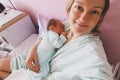 Mother and newborn after childbirth in maternity hospital room. Mother hugging her sleeping newborn baby Royalty Free Stock Photo