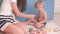 Mother painting on her little boy body making him ticklish