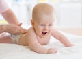 Mother physician massaging baby in bed in nursery Royalty Free Stock Photo