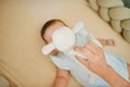 Mother playing with baby lying in a crib, 6 months old, top view, hidden face