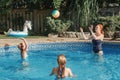 Mother playing ball with daughters children in swimming pool on home backyard. Mom and sisters siblings having fun in swimming Royalty Free Stock Photo