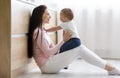 Mother playing with cute baby, sitting on floor in kitchen Royalty Free Stock Photo