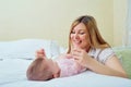 Mother playing with her baby on the bed. Mom smiles to her child Royalty Free Stock Photo