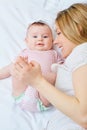 Mother playing with her baby on the bed. Mom smiles to her child Royalty Free Stock Photo