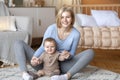 Mother playing with her infant child, sitting on bed Royalty Free Stock Photo