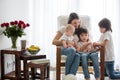 Mother, playing with her toddler boy and his older brother, reading book, smiling Royalty Free Stock Photo